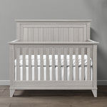 Load image into Gallery viewer, Gray wooden crib with white mattress against a gray wall
