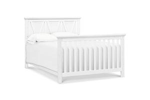 White crib converted to full size bed on a white background