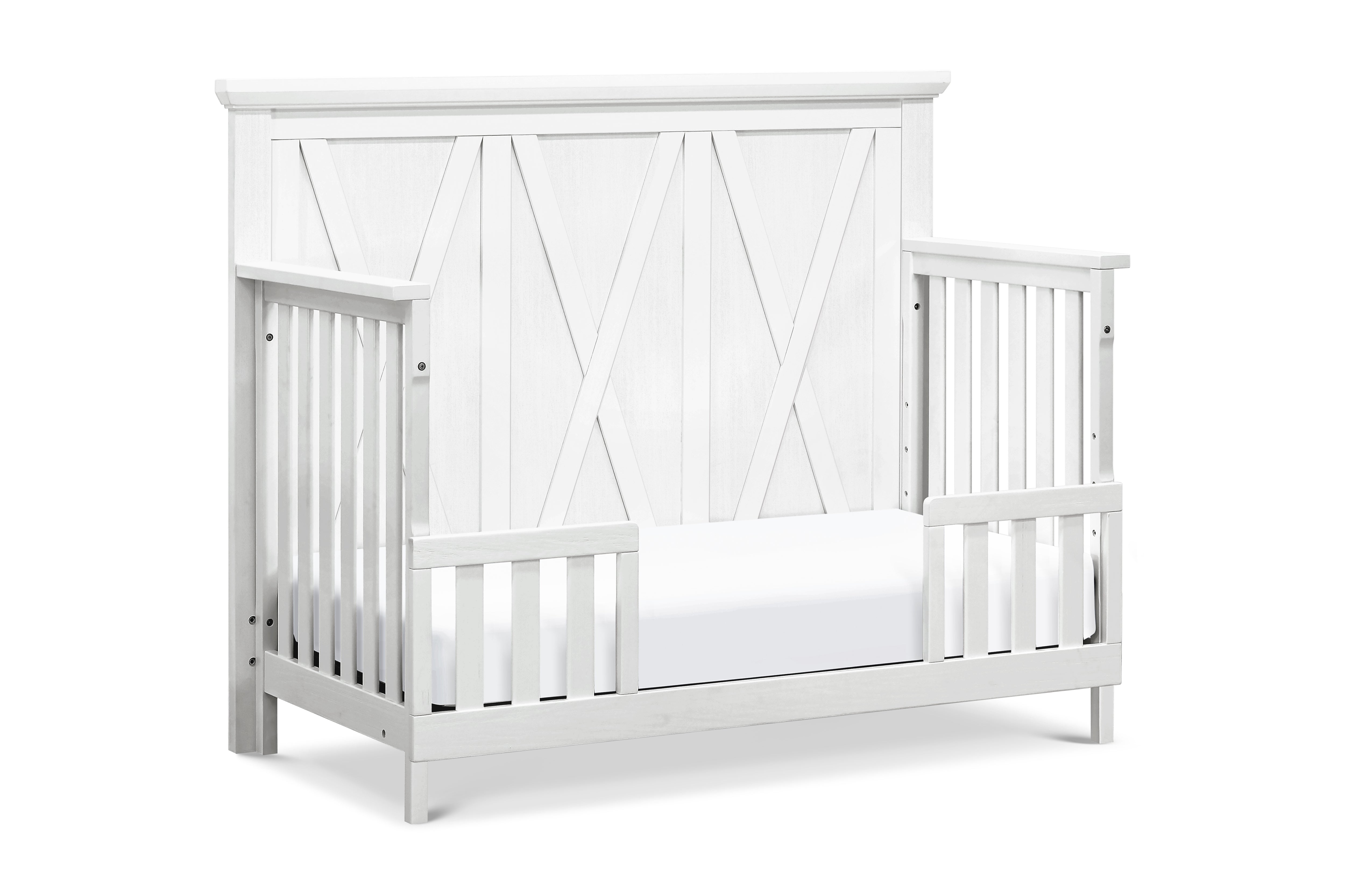 White crib set up as toddler bed with a cross-patterned design on a white background