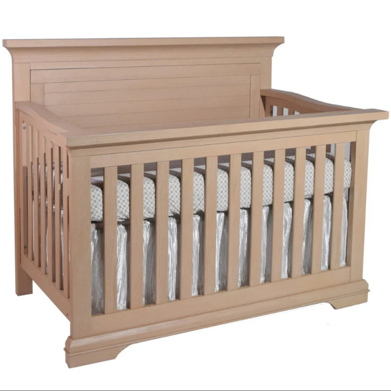 Beige crib with a white mattress on a white background