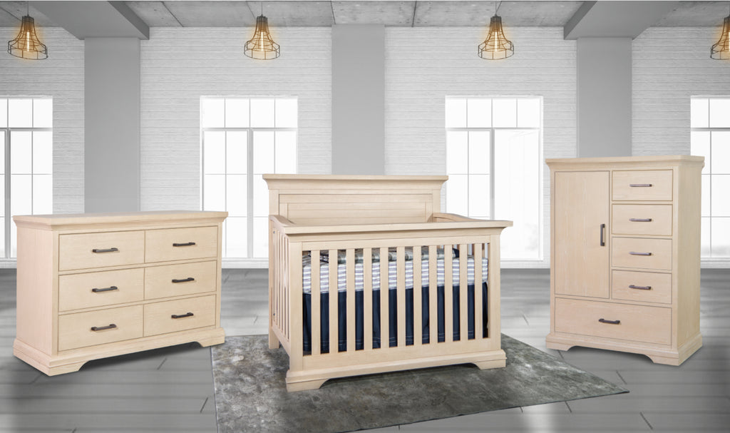 Beige nursery furniture set including a crib, dresser, and chest of drawers in a room with large windows.