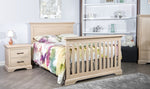 Load image into Gallery viewer, Beige crib converted to full size bed, with colorful bedding in a nursery setting
