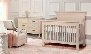 Nursery room with a crib, dresser, and chair in a soft color scheme.