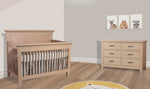 Load image into Gallery viewer, Wooden crib and dresser in a nursery with framed pictures on the wall.
