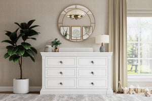 White dresser with decorative mirror and plants in a room with a window and curtains.