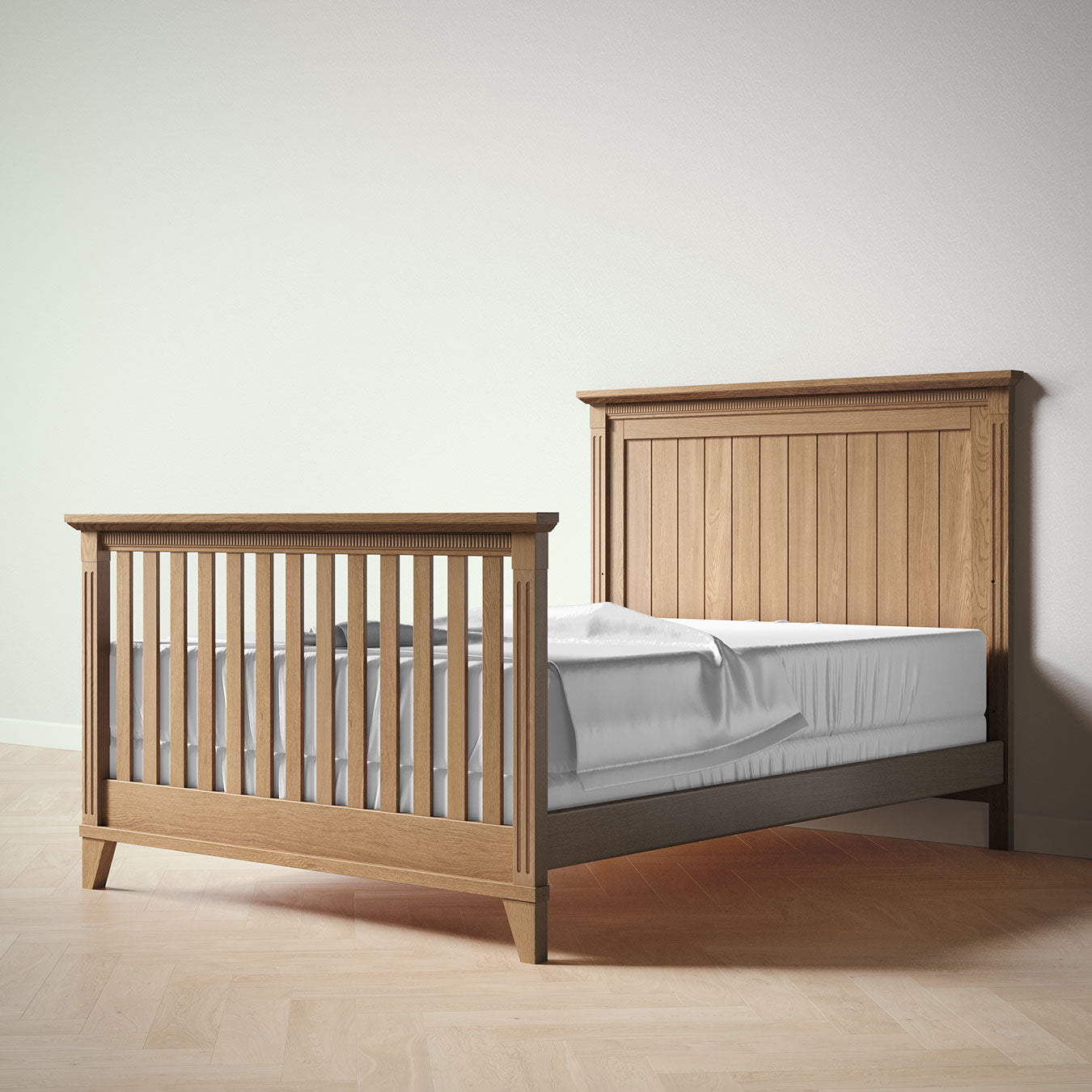 Wooden crib , converted to a full bed, with a mattress on a plain background