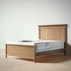 Wooden bed frame with mattress and blanket on a plain background