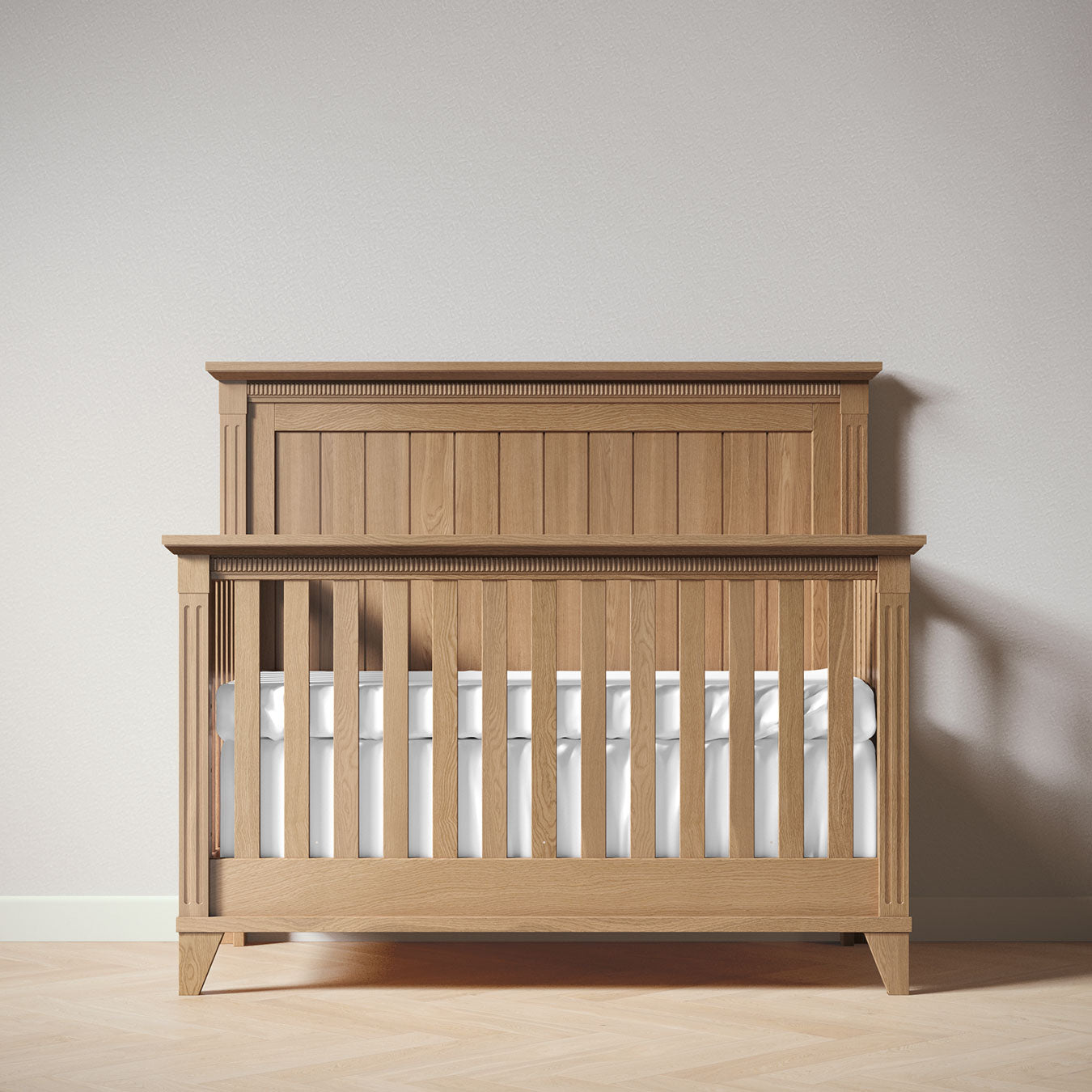 Wooden crib with white mattress against a plain wall
