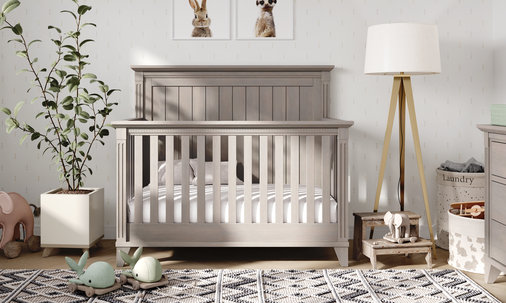Nursery room with a gray crib, lamp, and decorative items.