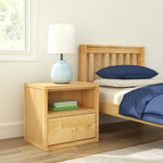Load image into Gallery viewer, Wooden nightstand with books and a lamp next to a bed with blue bedding.
