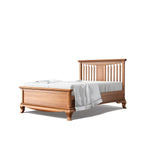 Load image into Gallery viewer, A classic wooden bed frame with a warm medium-brown finish, featuring a slatted headboard and footboard, styled with white bedding and a white throw blanket, set against a plain white background.
