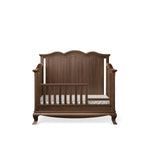 Load image into Gallery viewer, A dark brown wooden convertible crib with a tall arched headboard, side rails, and curved legs, shown on a plain white background.
