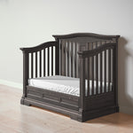 Load image into Gallery viewer, Dark wood crib, converted to daybed, with white mattress on a light wooden floor.
