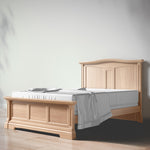 Load image into Gallery viewer, Wooden bed with white mattress and gray blanket against a plain wall
