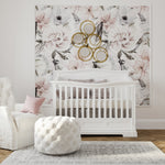 Load image into Gallery viewer, A styled nursery interior featuring a large floral wall mural with pink and white flowers, a white crib, a white tufted ottoman, a white armchair with a pink pillow, and a gold circular wall mirror arrangement.
