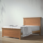 Load image into Gallery viewer, A light oak wood bed frame with a matching headboard and footboard, shown with white bedding on a light wood floor against a plain white wall.
