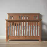 Load image into Gallery viewer, Wooden crib with white bedding against a plain wall
