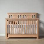 Load image into Gallery viewer, Wooden crib with a gray mattress against a plain wall

