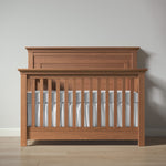 Load image into Gallery viewer, Wooden crib with white mattress against a plain wall

