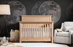 Load image into Gallery viewer, Nursery with wooden crib, gray bedding, and moon-themed wall decor.
