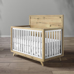 Load image into Gallery viewer, Wooden crib with white mattress in a room with gray walls and wooden floor.
