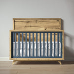 Load image into Gallery viewer, Wooden crib with blue sides and white mattress against a gray wall.
