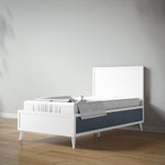 Load image into Gallery viewer, A modern full bed with a white finish and dark blue-gray storage drawers underneath, shown on a light wood floor against a neutral gray wall.
