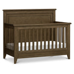 Load image into Gallery viewer, A wooden baby crib shown on a clean white background. The crib is finished in a medium brown wood grain finish, and a white mattress is visible inside.
