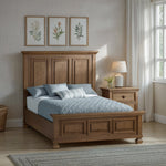 Load image into Gallery viewer, Wooden bed in a bedroom with floral artwork on the wall and a lamp on a nightstand.
