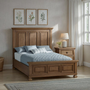 Wooden bed in a bedroom with floral artwork on the wall and a lamp on a nightstand.