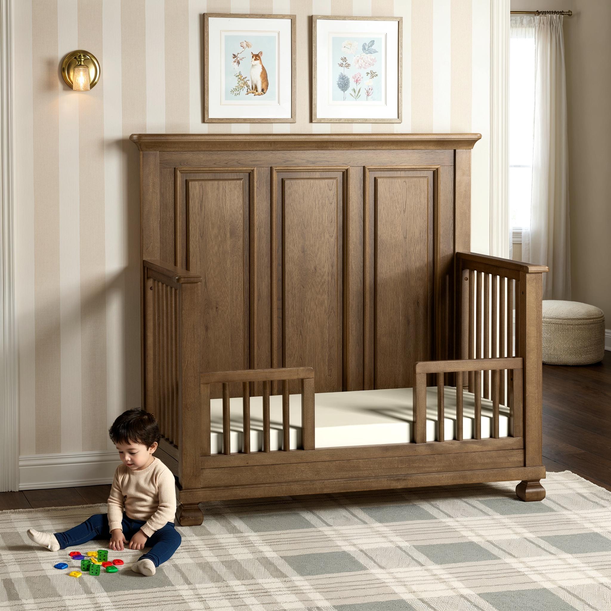 Child playing with toys on the floor next to a wooden crib in a nursery.